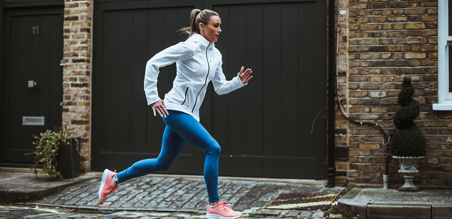 Lady running in the cobbled residential streets in winter running gear